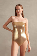 Model wearing the Timeless Metallic Strapless Swimsuit in gold color styled for a beachwear look