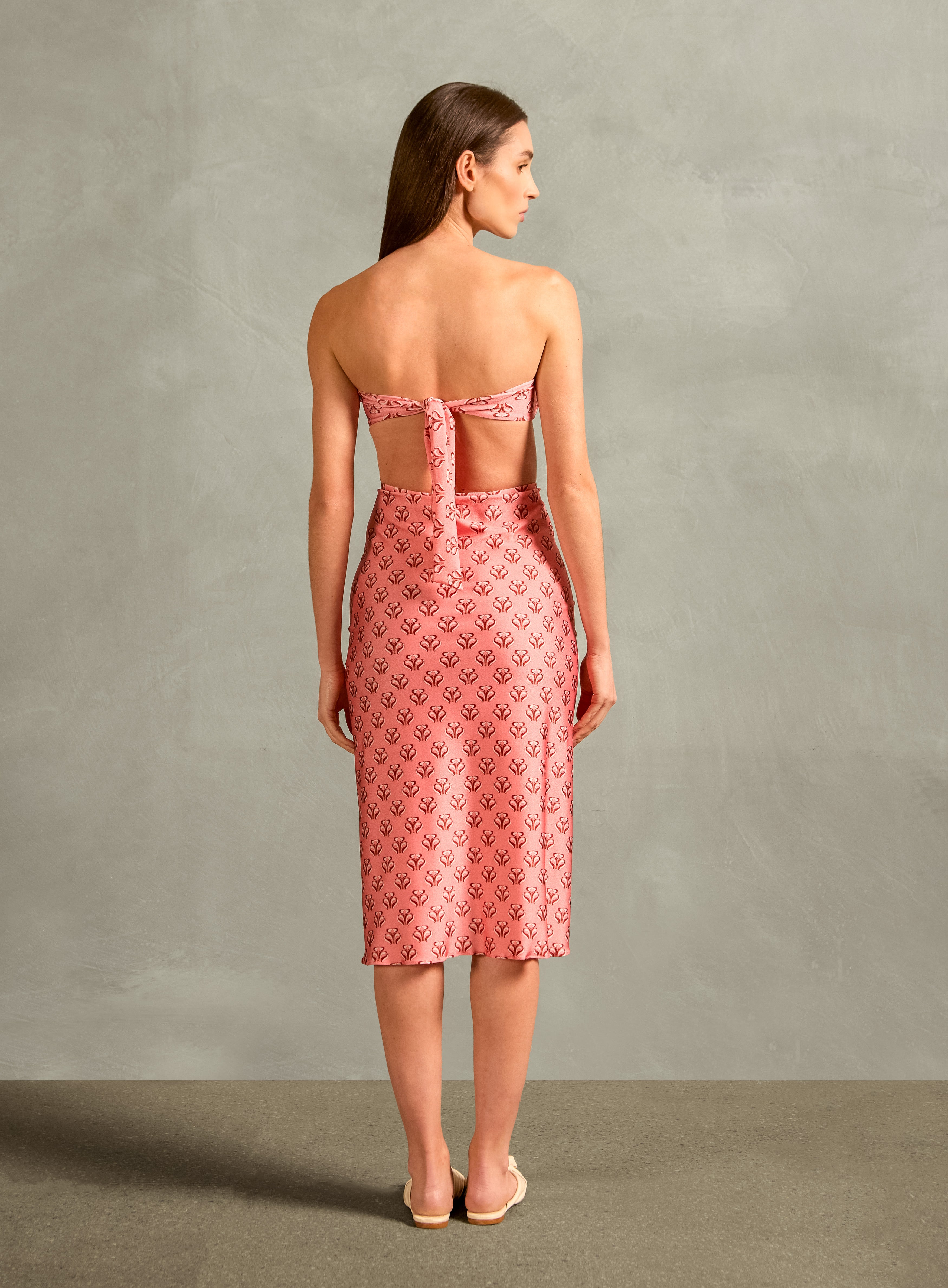 Model wearing the Vintage Lily Frilled Midi Skirt showcasing the back of it's classic AD references, with a pink print, on a stretchy fabric.