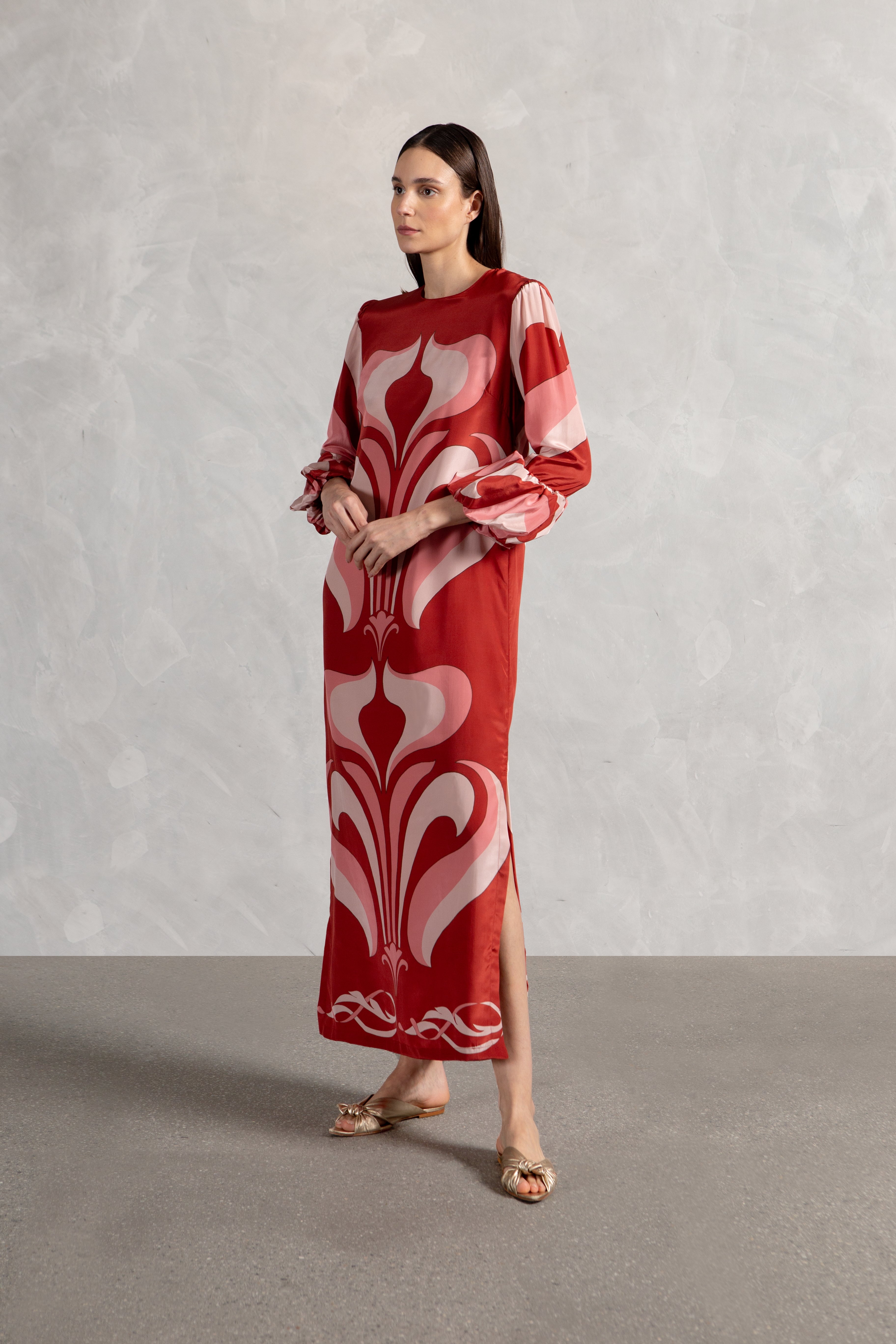 Model wearing the Vintage Lily Long Dress in Red showcasing the front of it's long sleeves piece, on a silk fabric.