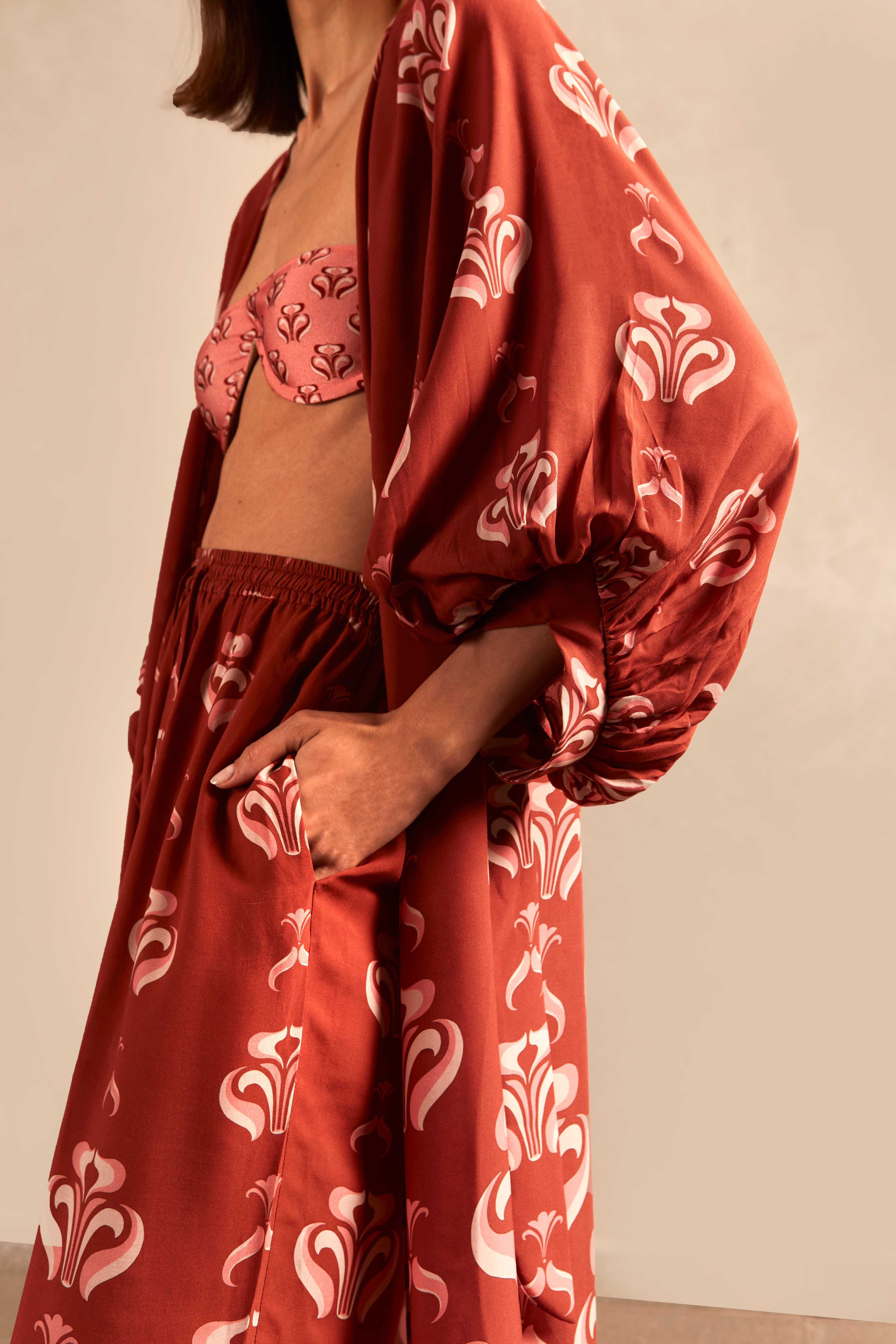 Model wearing the Vintage Lily Long Robe showcasing the close up of it's vintage-inspired dark red with pink print, on a viscose fabric.