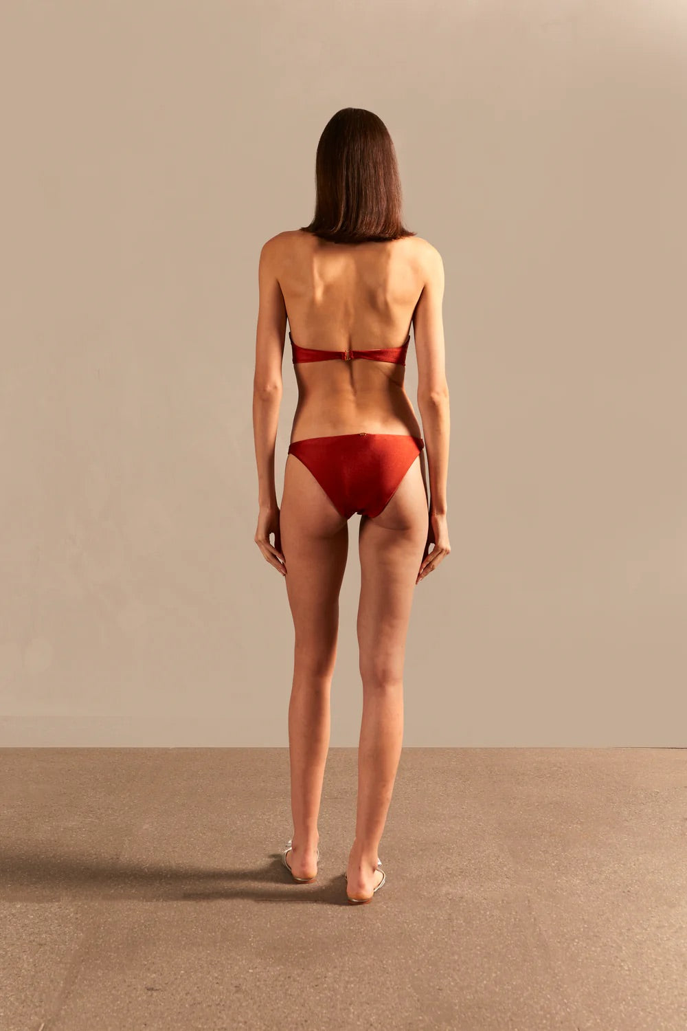 Model wearing the Vintage Lily Solid Red Strapless Bikini showcasing the back of it's structured top, on a stretchy fabric.