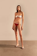 Model wearing the Vintage Lily Solid Sunglasses Bikini showcasing the front of it's structured red and off white top, on a stretchy fabric.