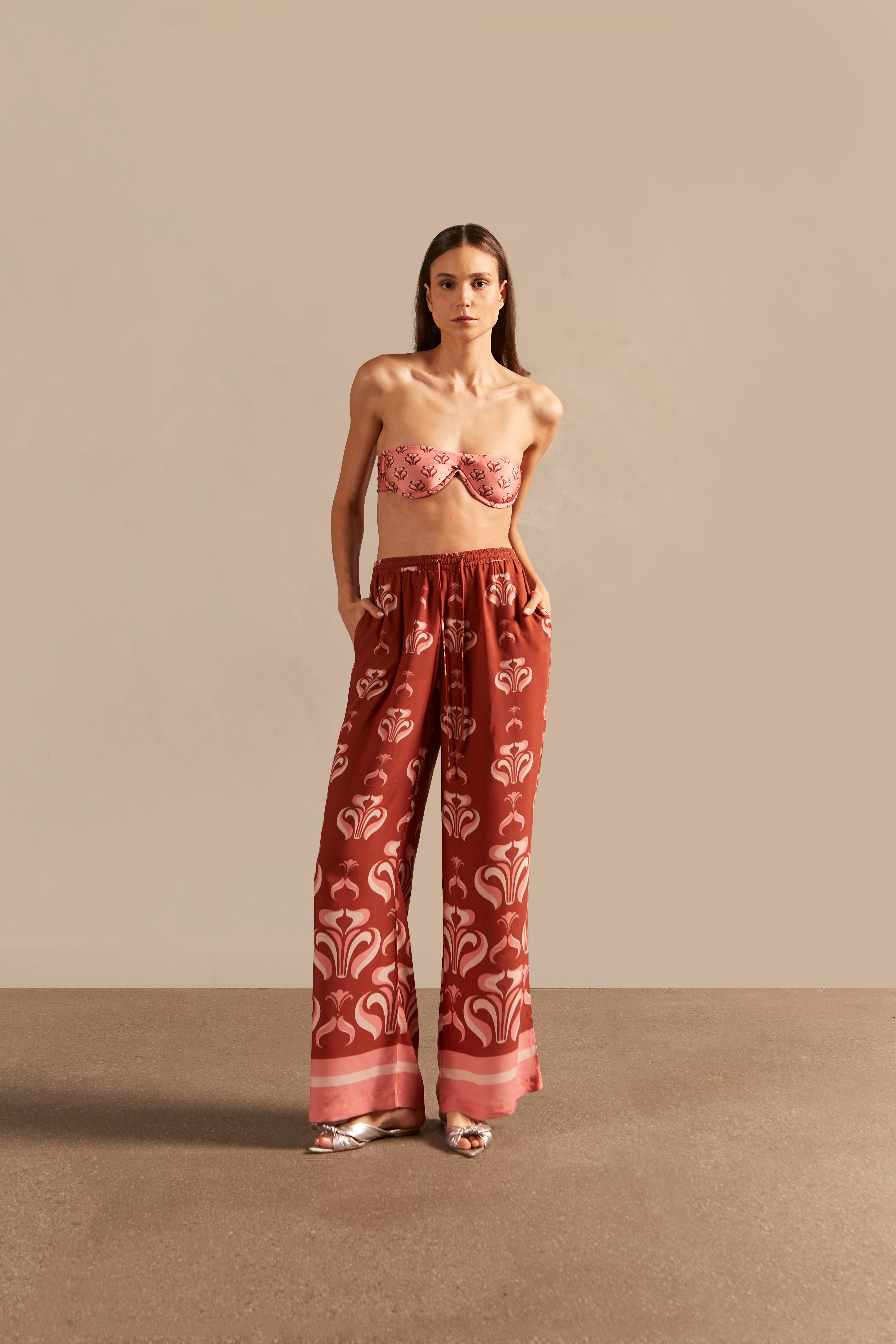 Model wearing the Vintage Lily Wide-Leg Pants showcasing the front of it's vintage inspired dark red and pink print, on a viscose fabric.