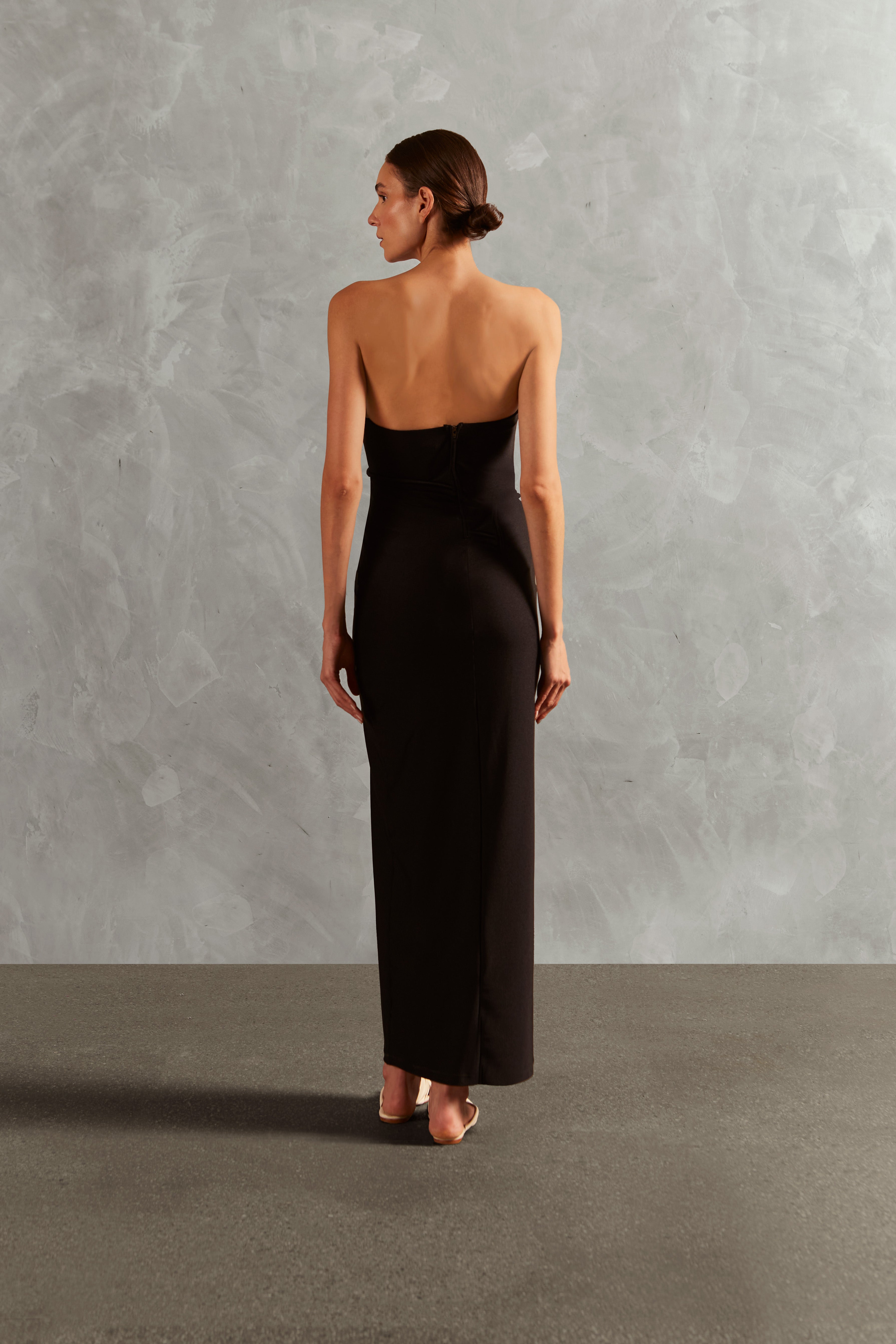 Model wearing the Waves Strapless Long Dress Back showcasing its Black color on 85% Polyamide 15% Elastane fabric, styled for a evening look.  