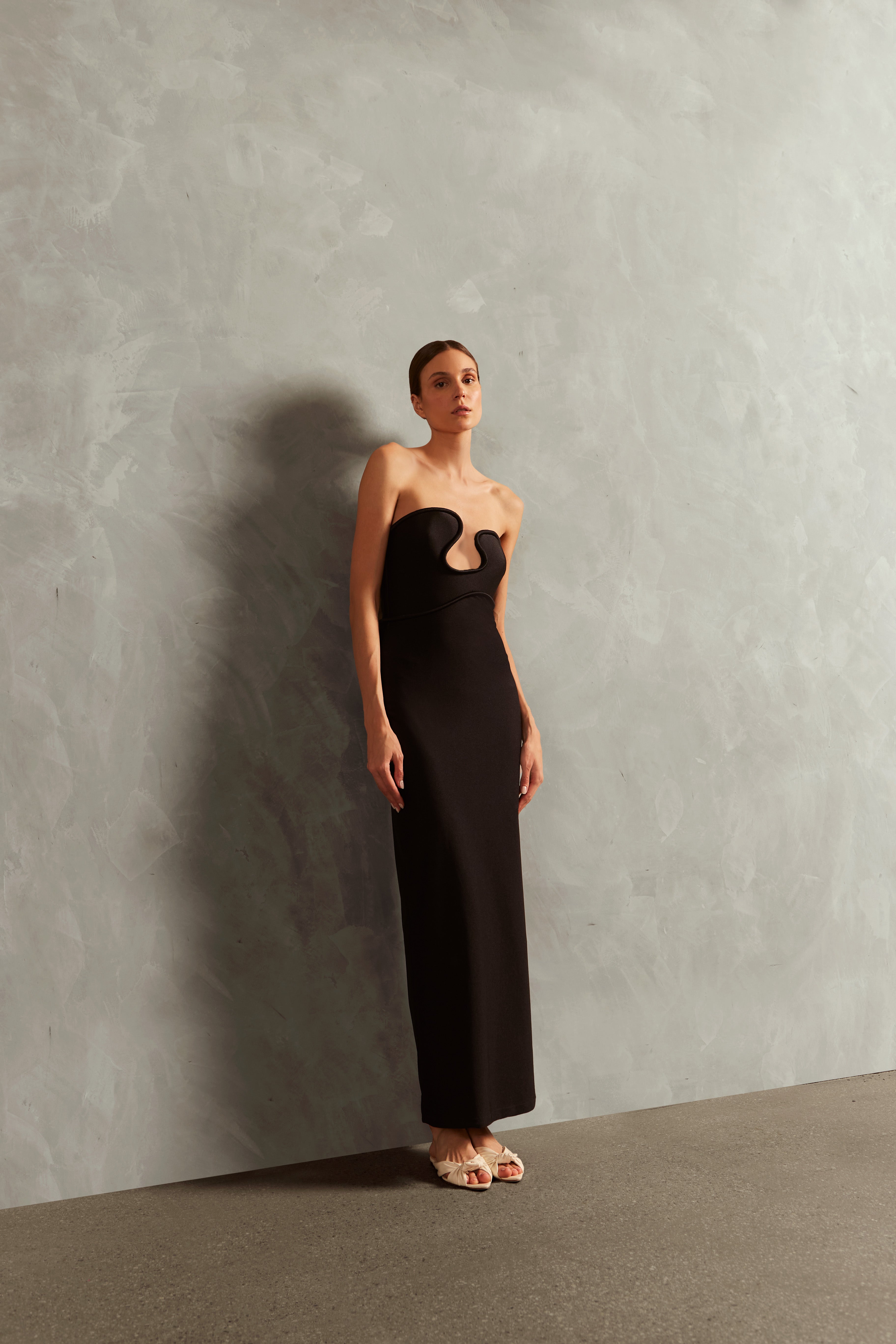 Model wearing the Waves Strapless Long Dress Front showcasing its Black color on 85% Polyamide 15% Elastane fabric, styled for a evening look.  