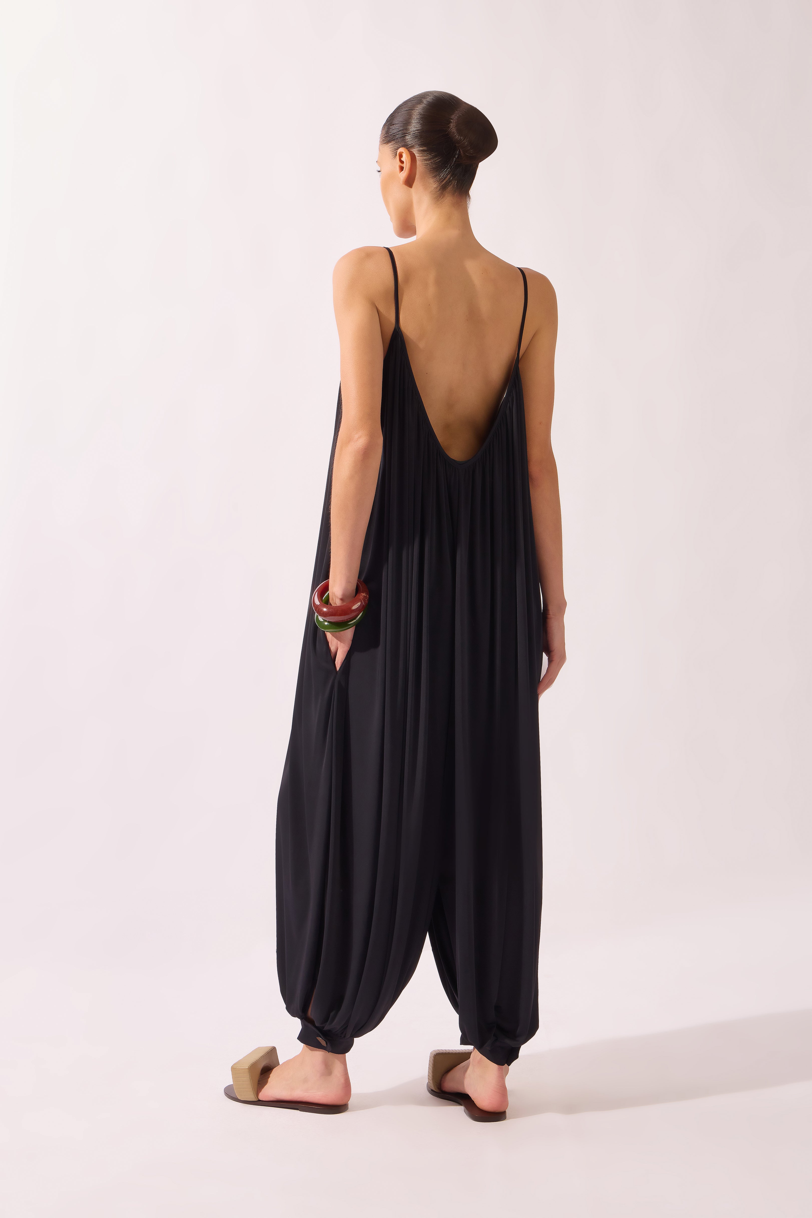 Model wearing the Wide Jersey Jumpsuit back color black, made from 85% polyamide 15% elastane, styled for a beachwear look