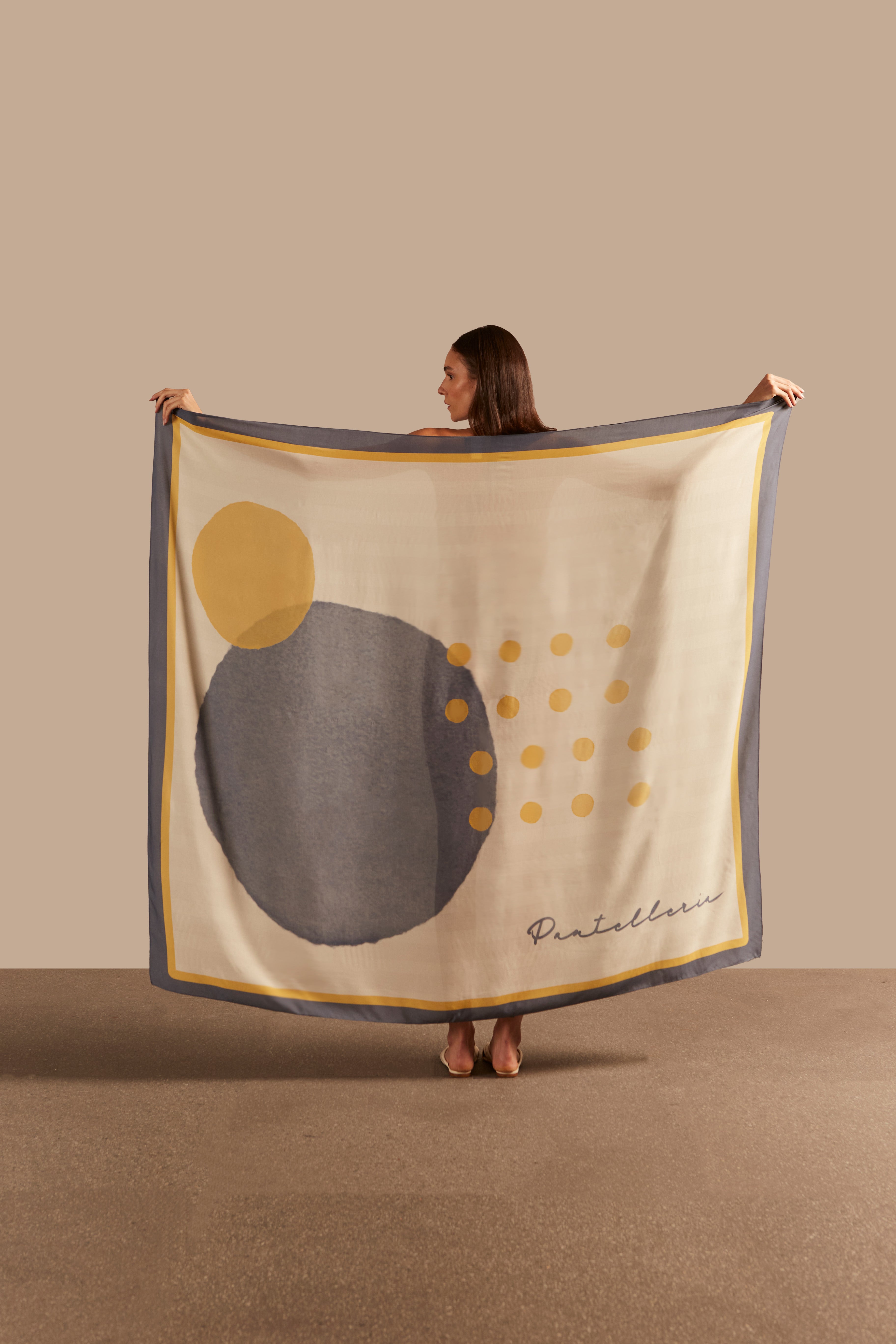 Model holding the Golden Age Panneaux, showcasing its geometric blue and yellow print on off-white viscose fabric.