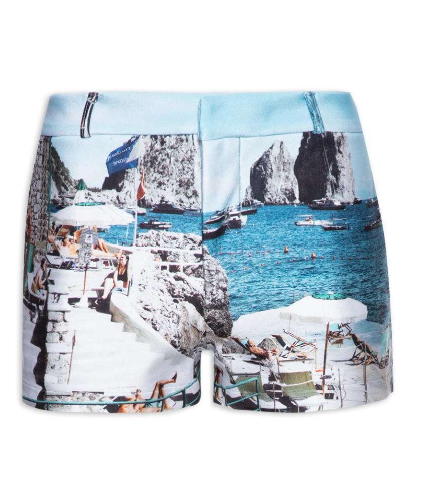 Flat-lay of Adriana Degreas' Postcard Genderless Shorts in blue with postcard print, highlighting the pockets and low-waist design.